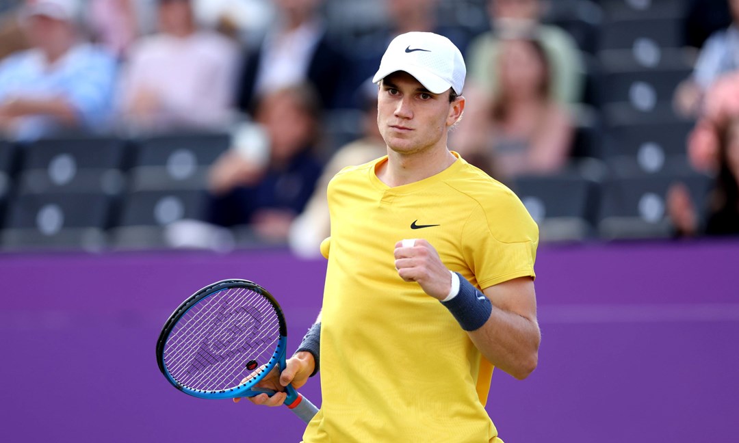 Jack draper wearing a yellow shirt and white hat clenching his fist on court at the cinch Championships while holding his tennis racket