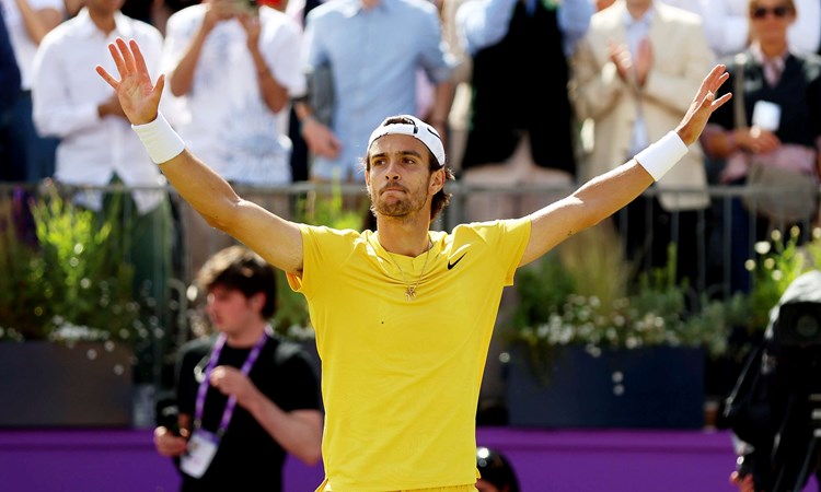 Lorenzo Musetti wearing yellow tshirt and yellow shorts while holding his hands up in the air after reaching the final of the cinch Championships