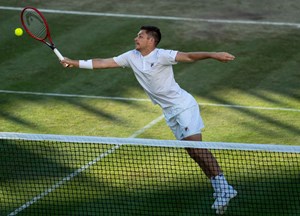 Neal Skupski wearing a white shirt and white shorts while reaching for a forehand on court at wimbledon