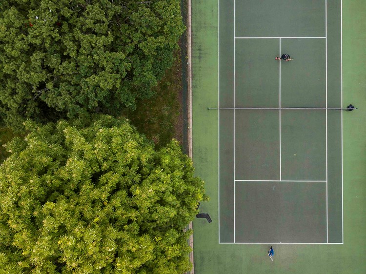 Tennis match taking place on a park tennis court